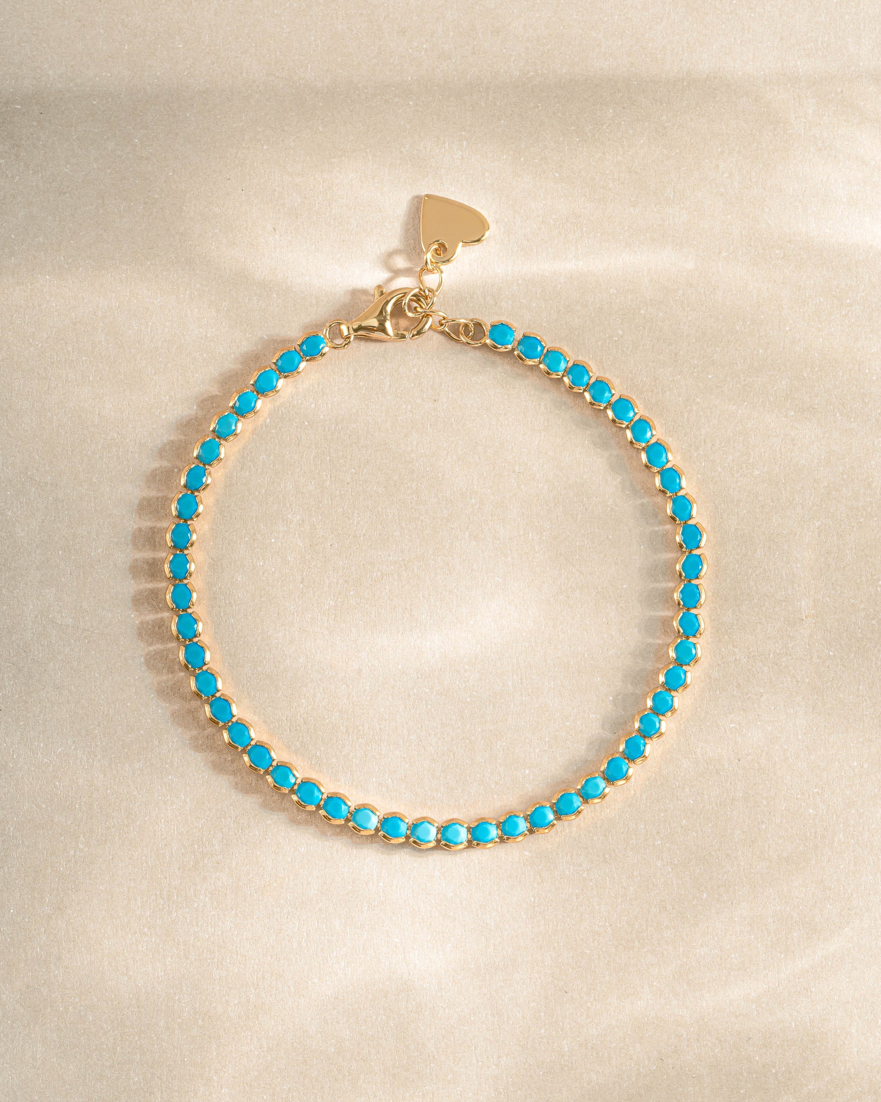 turquoise tennis bracelet in gold on a simple background