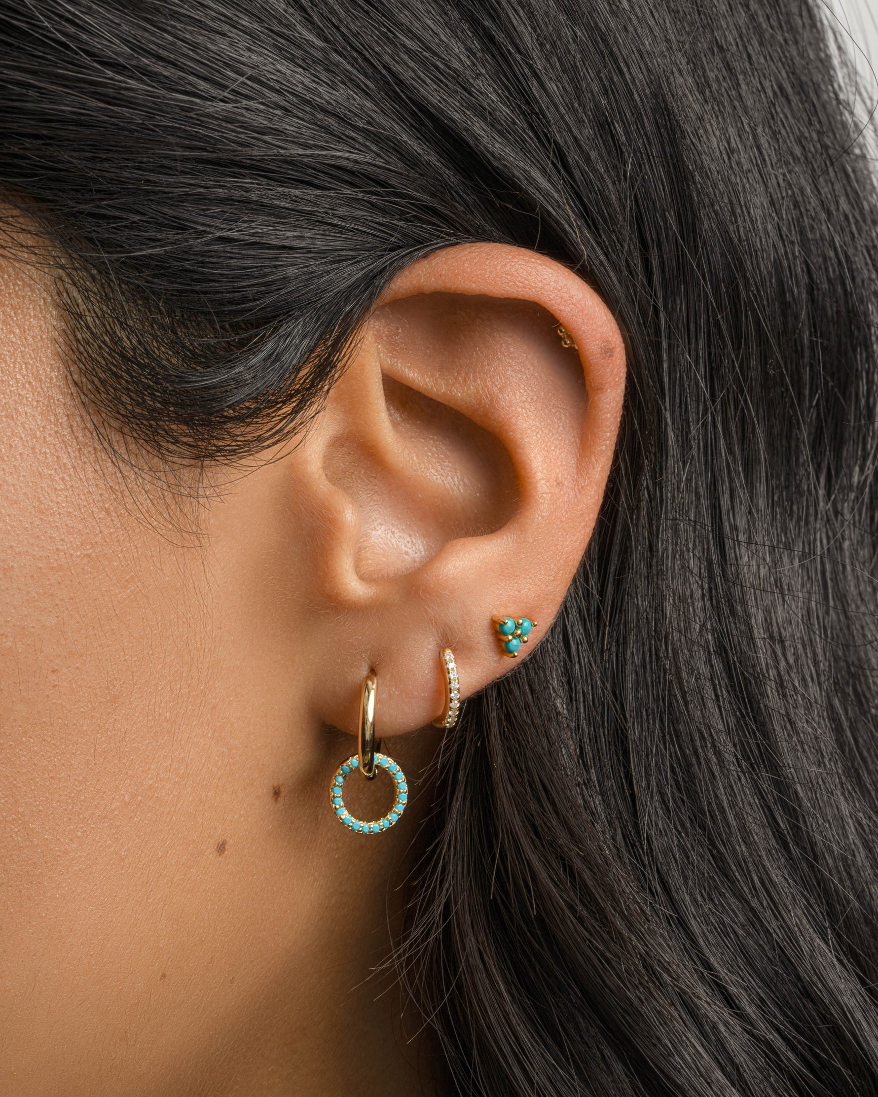 Gold Sami Jewels turquoise three stone stud earrings worn by a model, showcasing elegant jewelry with vibrant turquoise stones.