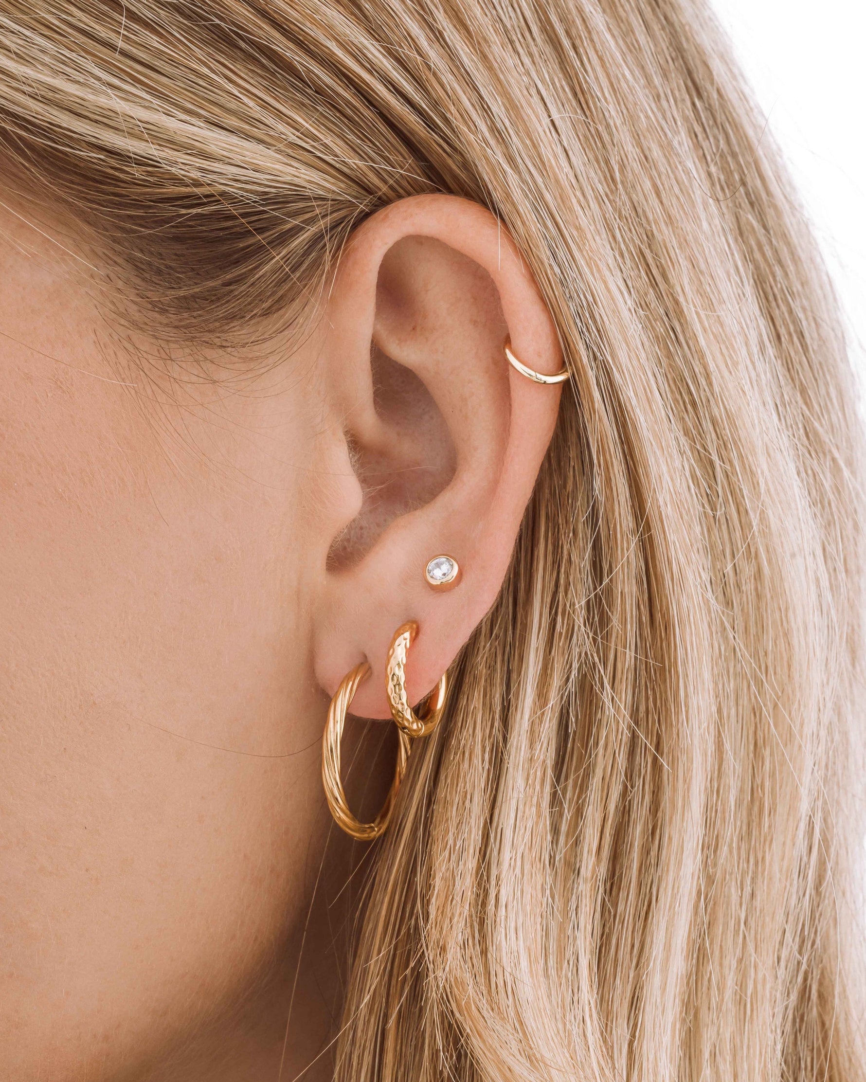 Gold stainless steel SS Twisted Hoops earrings by Sami Jewels, featuring a sleek twisted hoop design on a model.