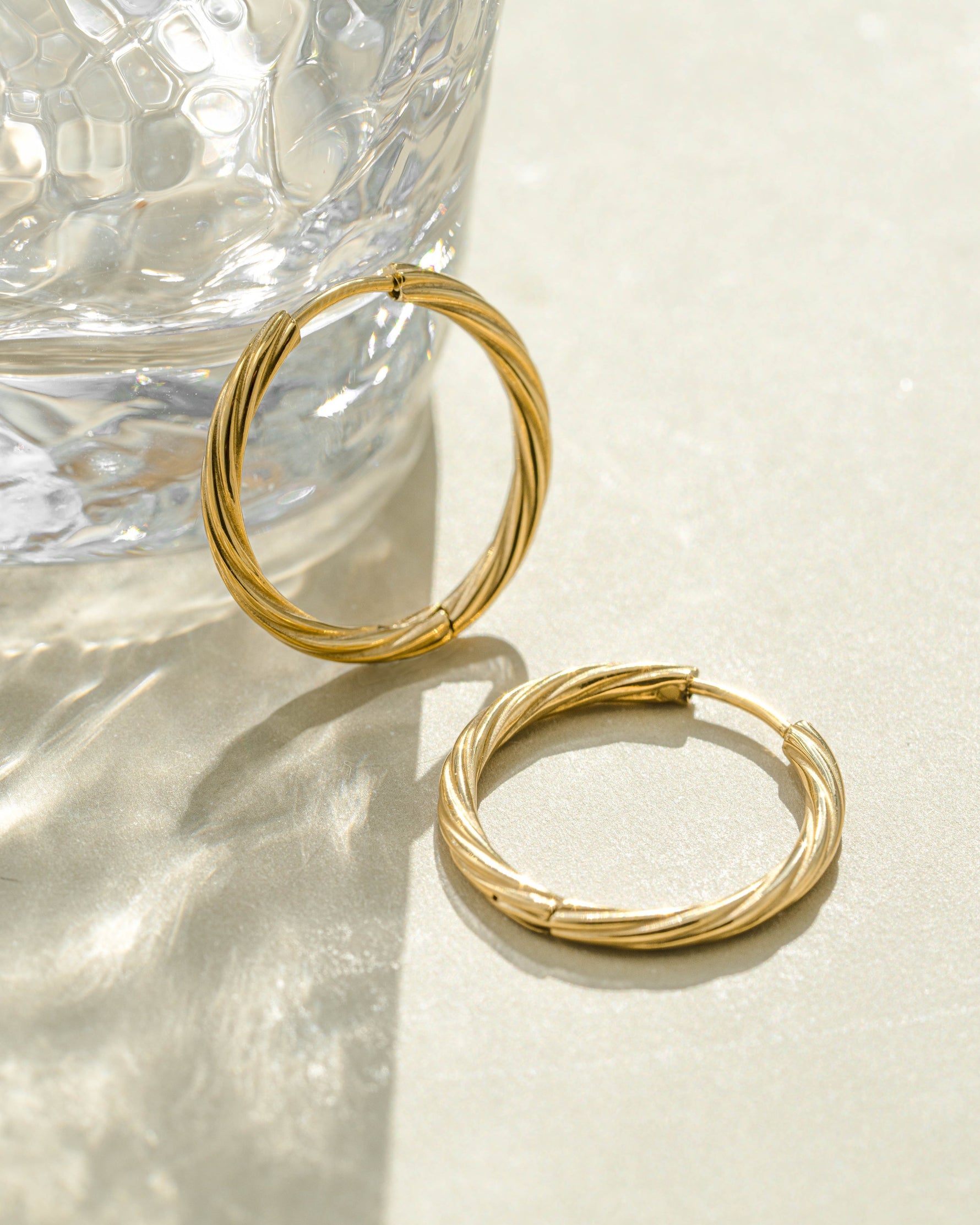Gold stainless steel twisted hoop earrings from Sami Jewels, waterproof earrings with a stylish twisted design.
