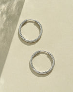 Close-up of silver stainless steel SS Twisted Hoops earrings by Sami Jewels, showcasing their twisted design and waterproof finish.