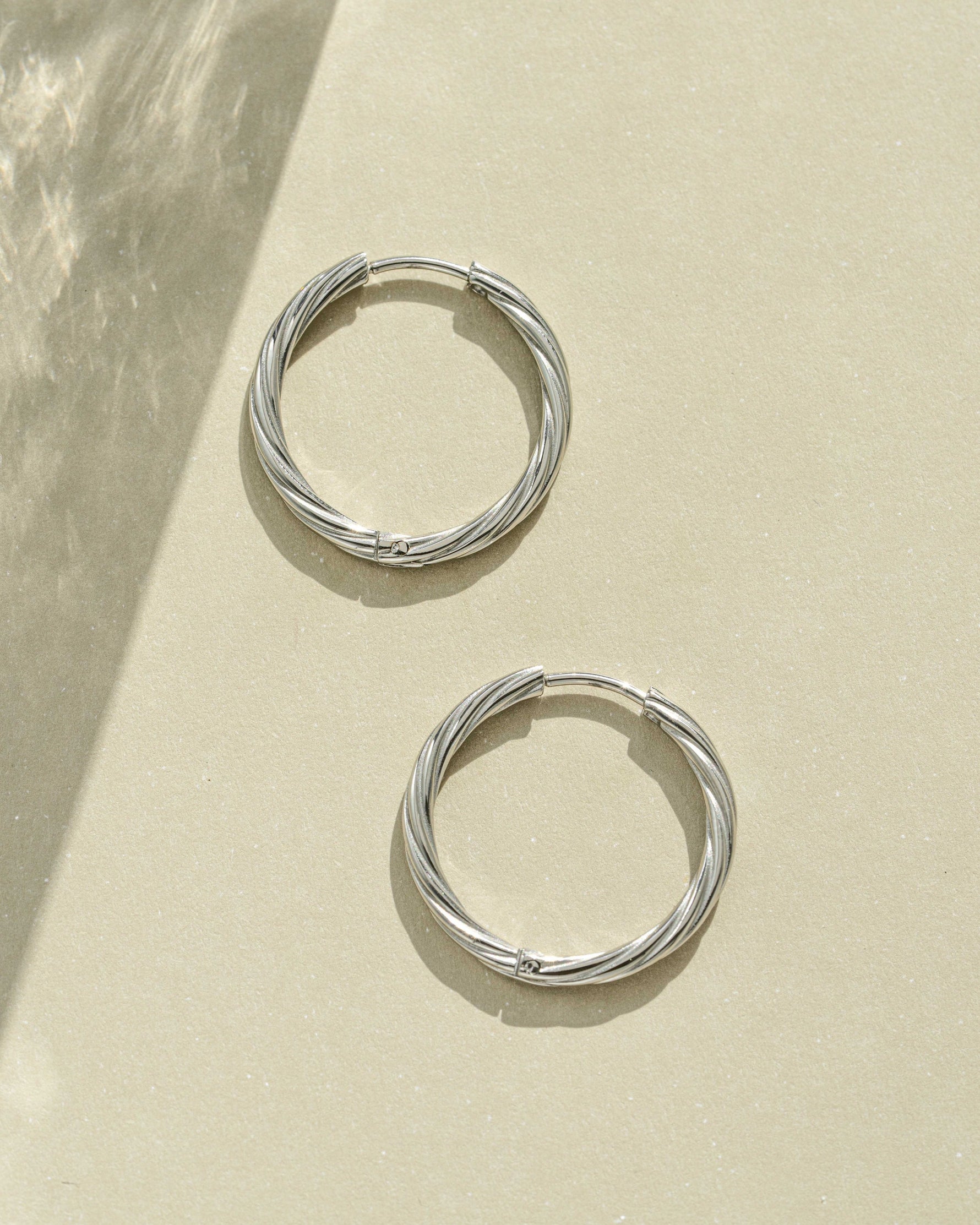 Close-up of silver stainless steel SS Twisted Hoops earrings by Sami Jewels, showcasing their twisted design and waterproof finish.