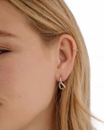 Silver stainless steel SS twisted oval hoop earrings by Sami Jewels, featuring a sleek, waterproof design on a model.