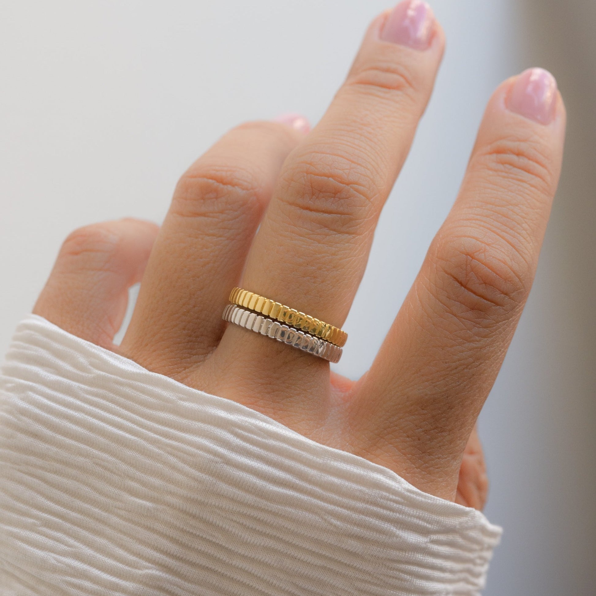 model wearing gold and sterling silver textured ring stack