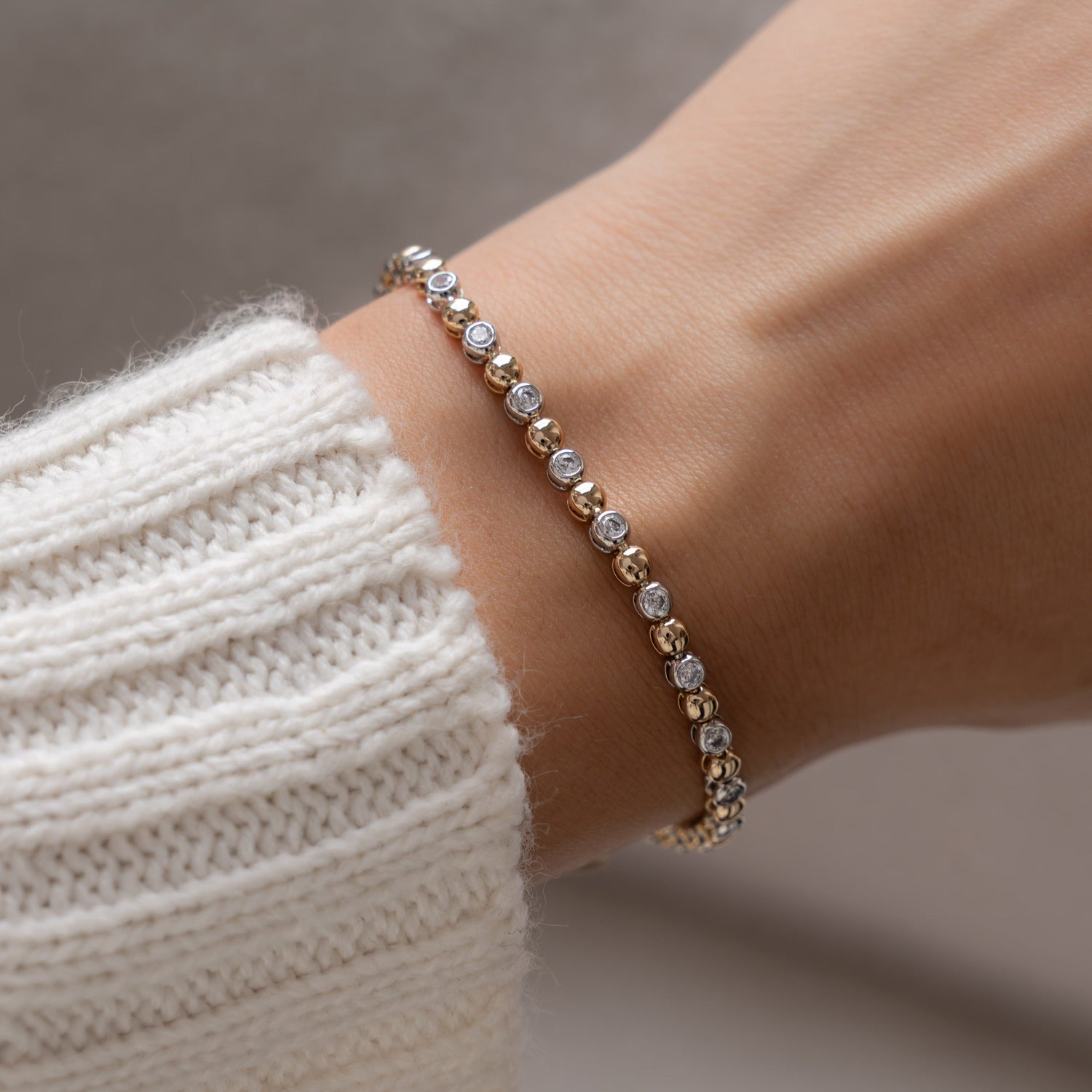 Model wearing mixed metal jewelry with diamonds.