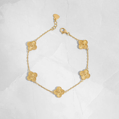 Close-up of a gold clover jewelry charm bracelet highlighting fine detailing.