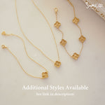 flat lay of matching four leaf clover necklace and charm bracelet in gold showcasing coordinated jewelry set.