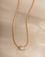 Gold flatlay of Sami Jewels white CZ baguette bezel statement necklace showcasing sparkling rectangular stones.
