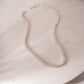 a white necklace on a marble surface