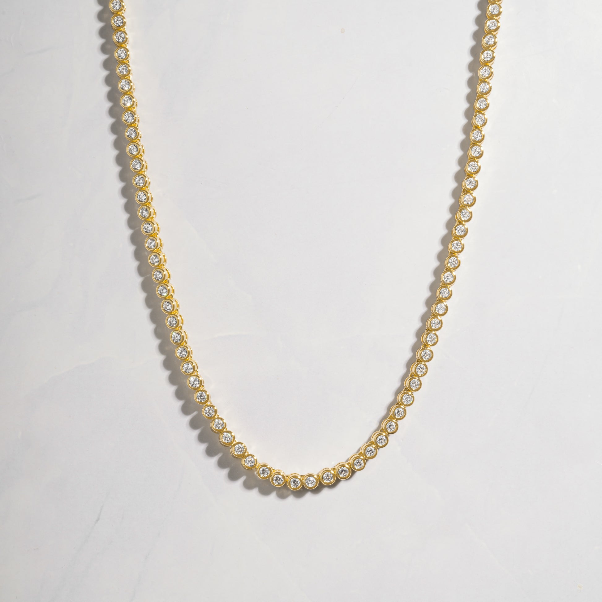 a gold necklace with pearls on a white background