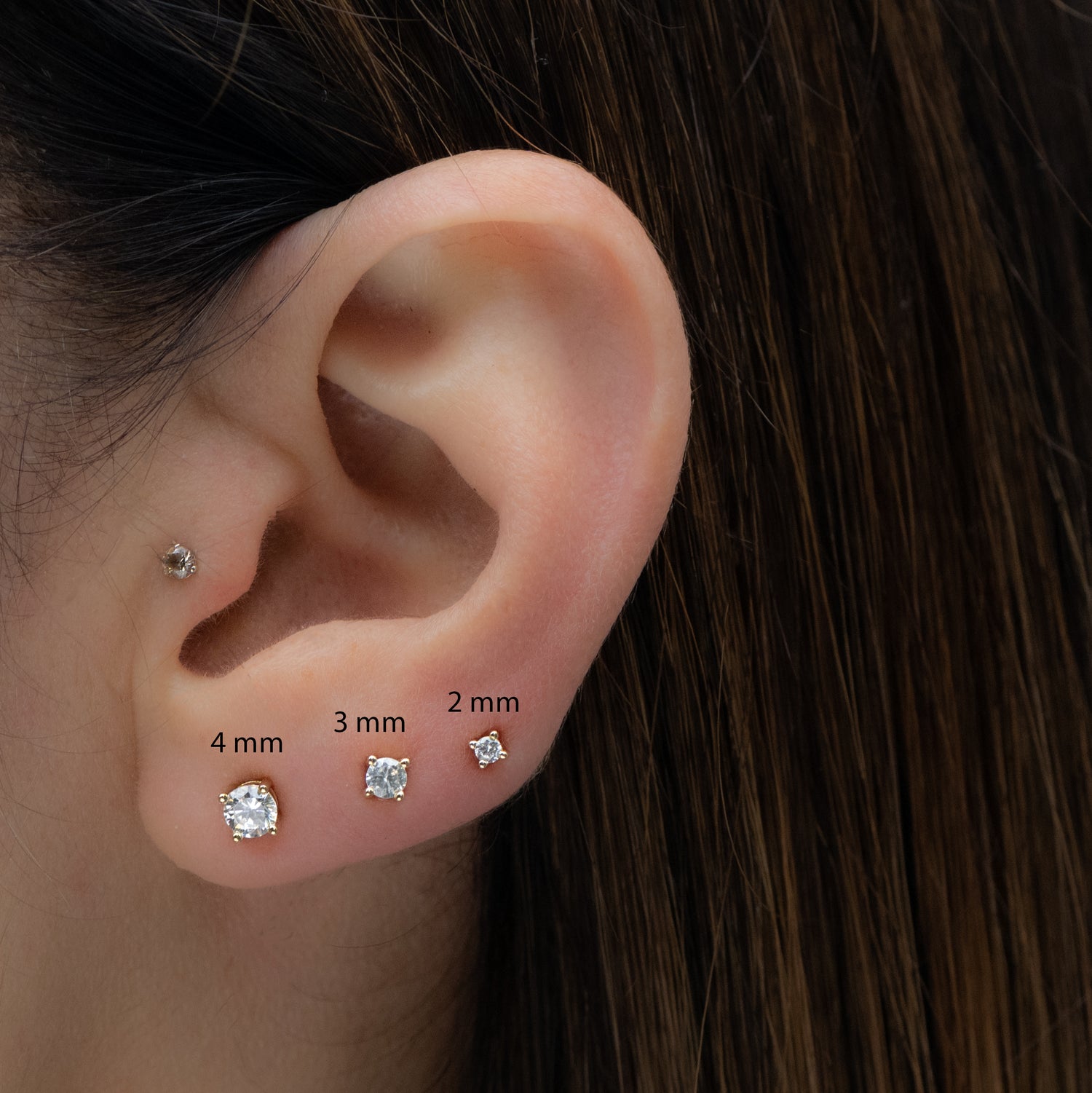 Multiple sizes of diamond cz stud earrings shown on models ear, 4mm, 3mm and 2mm sizes