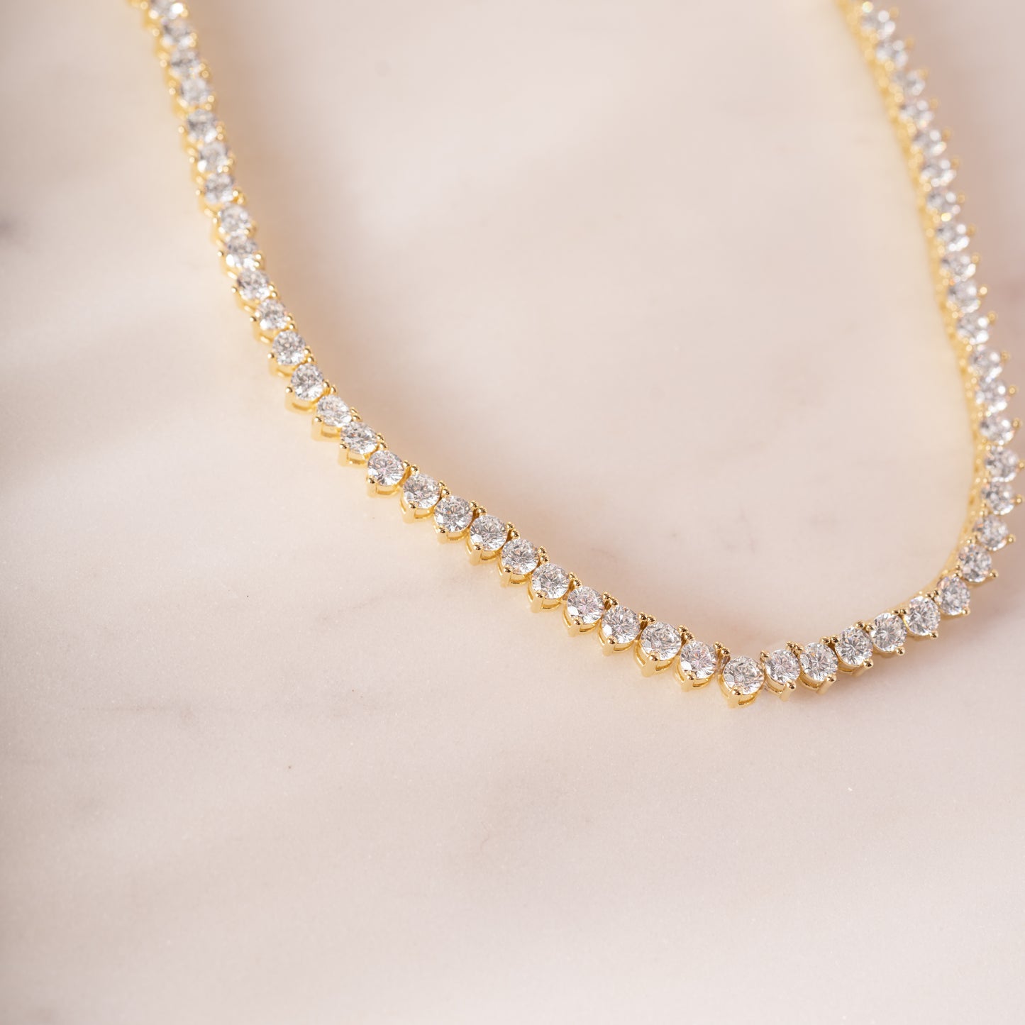 a diamond necklace on a white marble surface