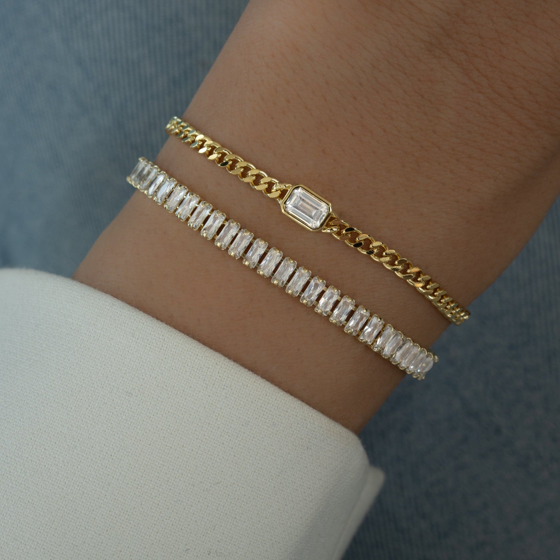 model wearing gold diamond baguette tennis bracelet and bezel baguette charm on curb chain bracelet