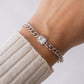 model wearing halo baguette charm on silver cuban link bracelet
