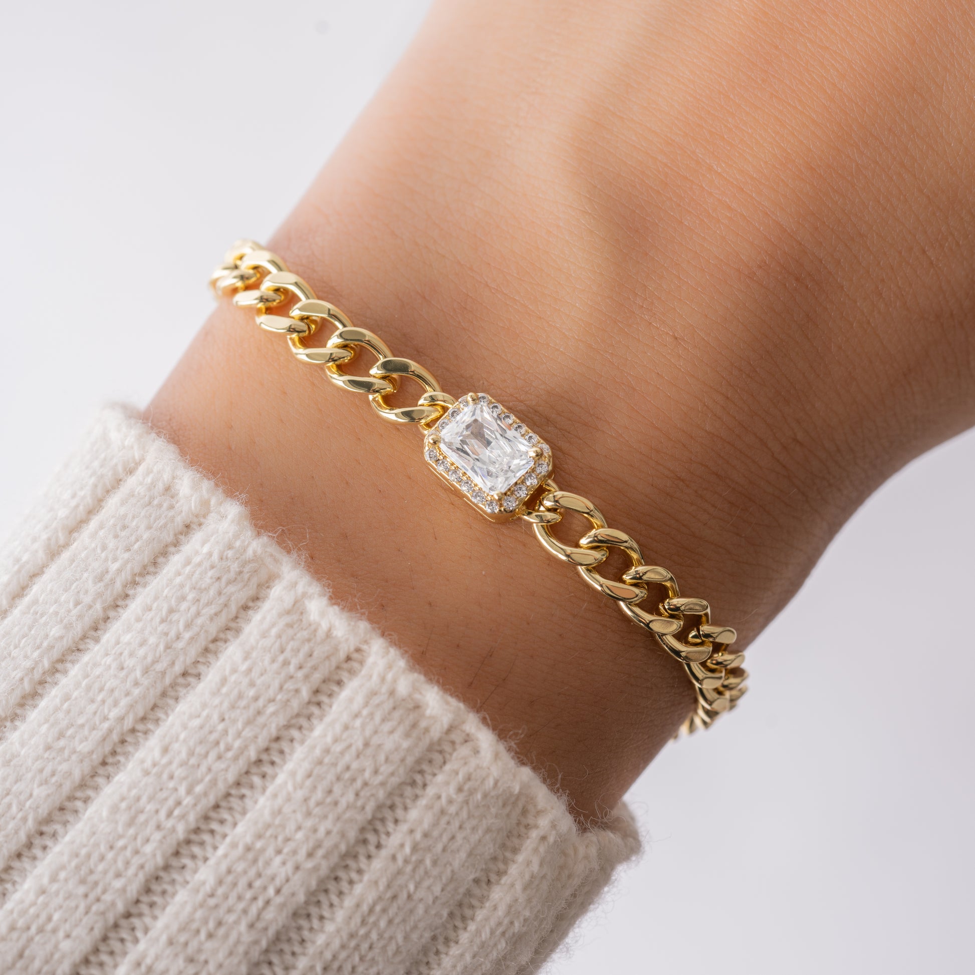 model wearing gold cuban link bracelet with halo baguette charm