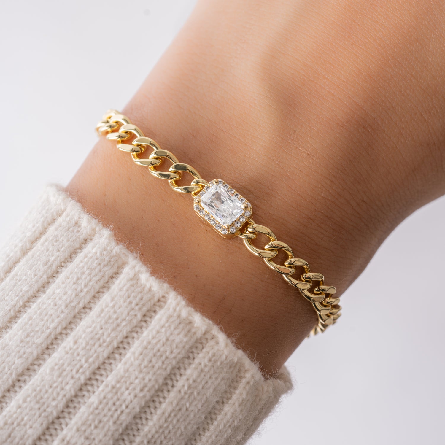 model wearing gold cuban link bracelet with halo baguette charm