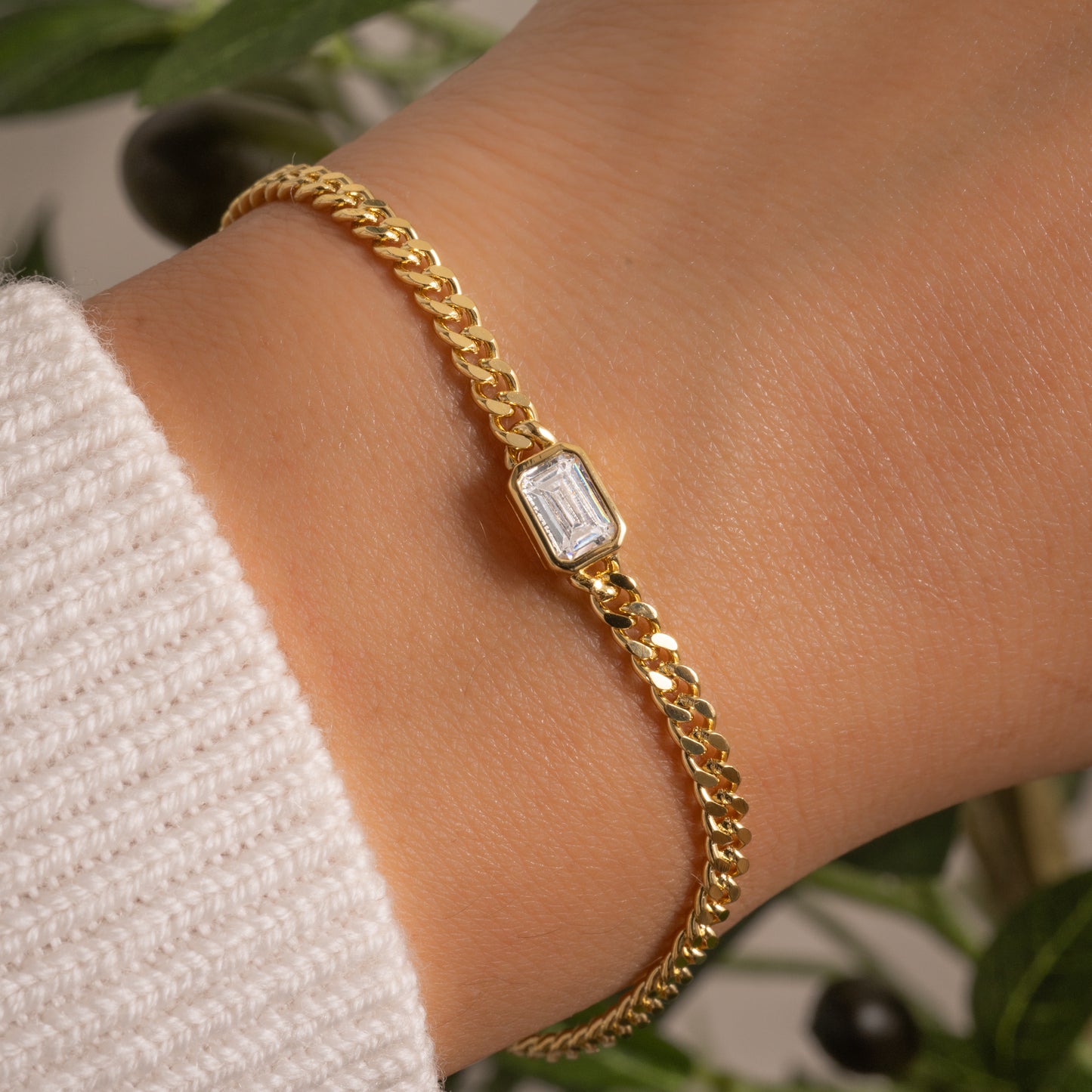 model wearing diamond bezel baguette charm on dainty gold curb chain bracelet