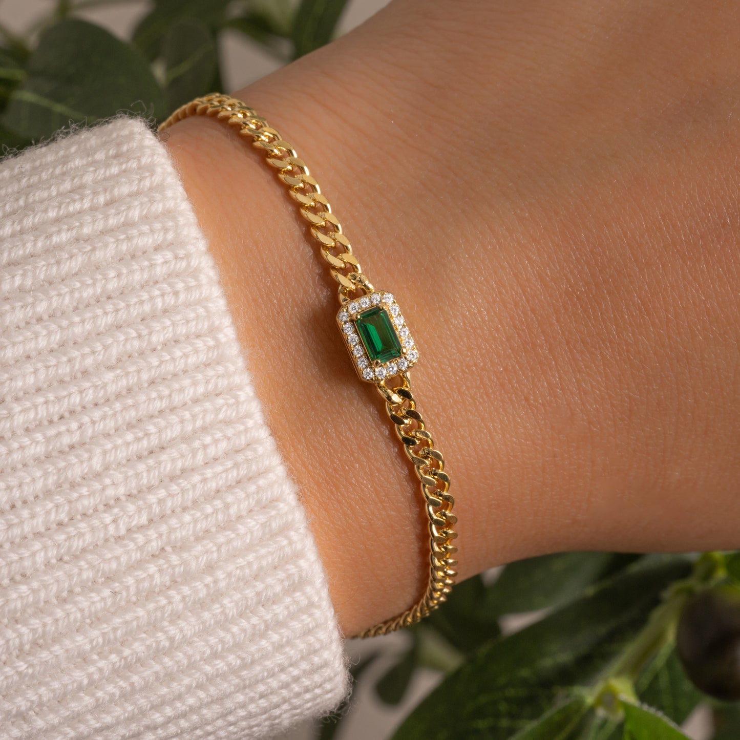 model wearing gold curb chain bracelet with emerald halo charm