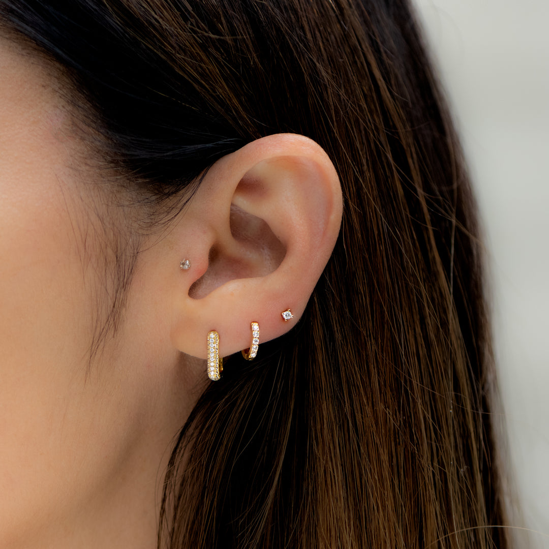 Model wearing pavé gold huggies and stud earrings.