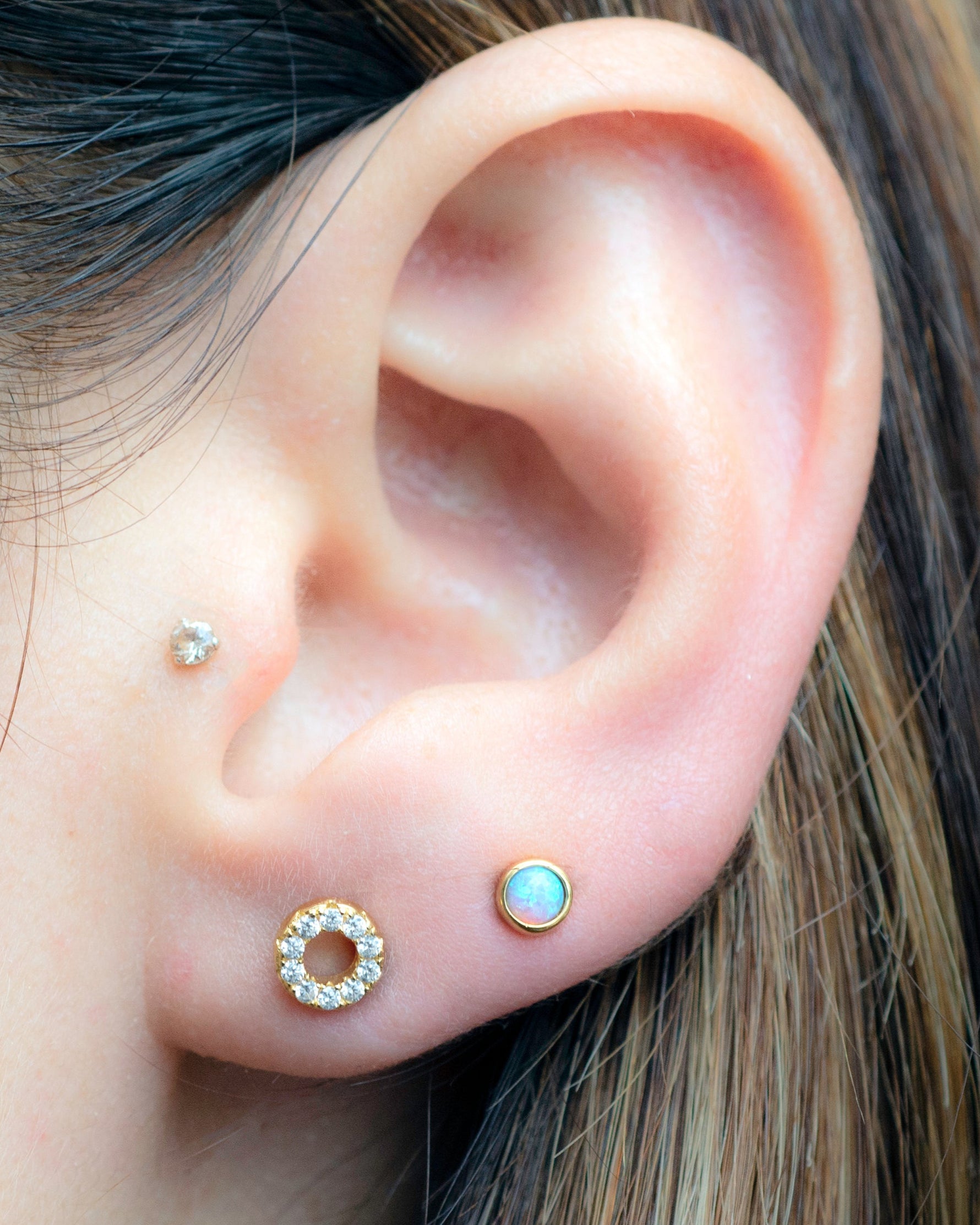 Model wearing gold circle and opal studs