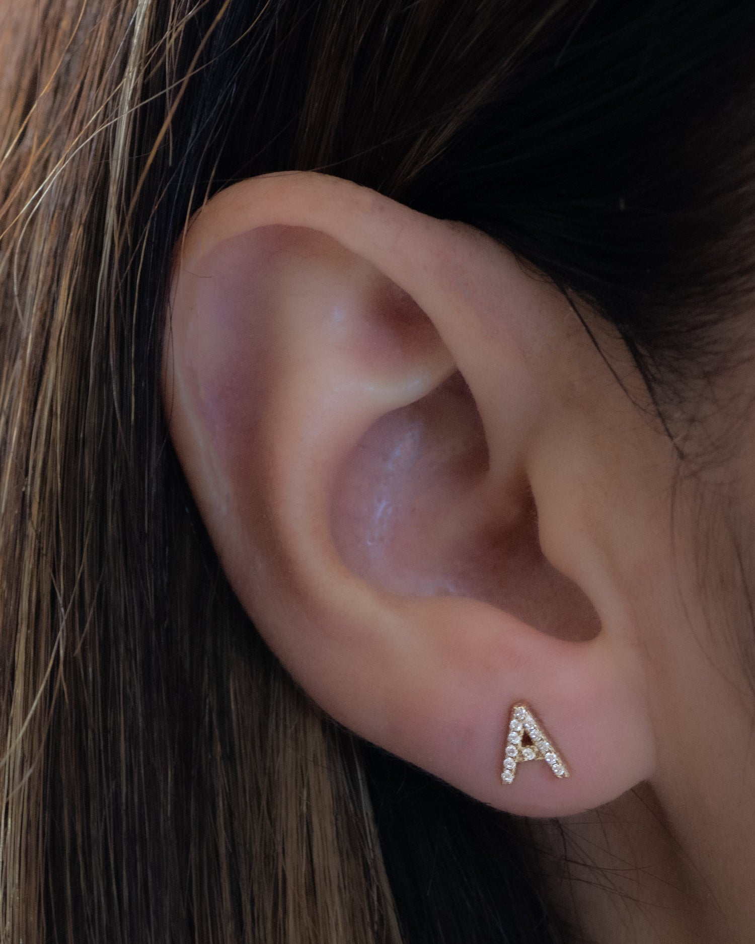 Model wearing custom letter stud earrings in the letter "A". 
