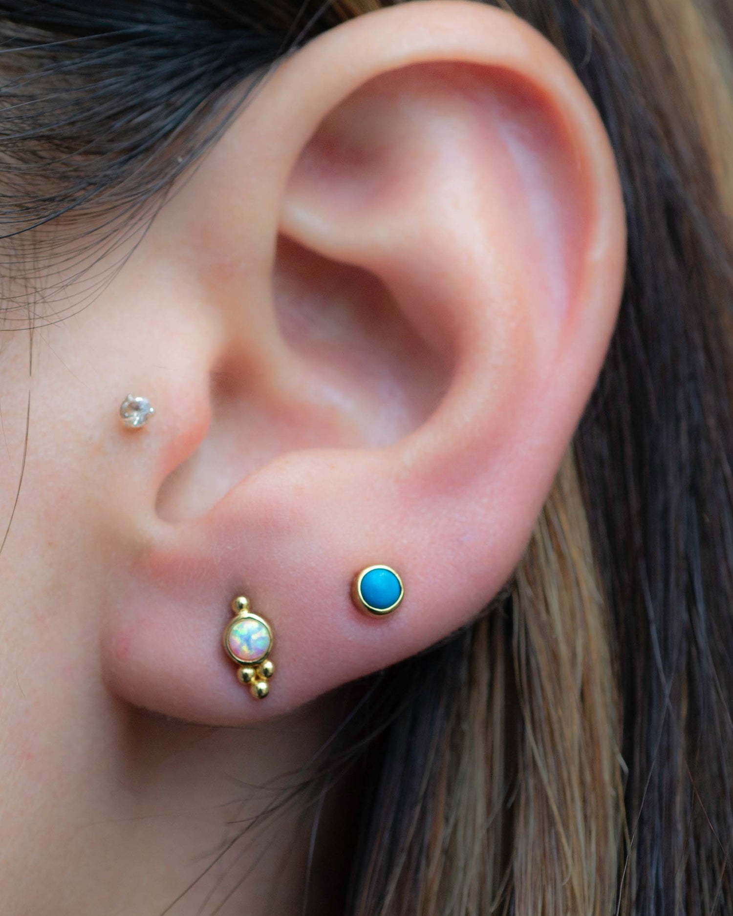 Model wearing turquoise and opal round stud earrings for a pop of color. 