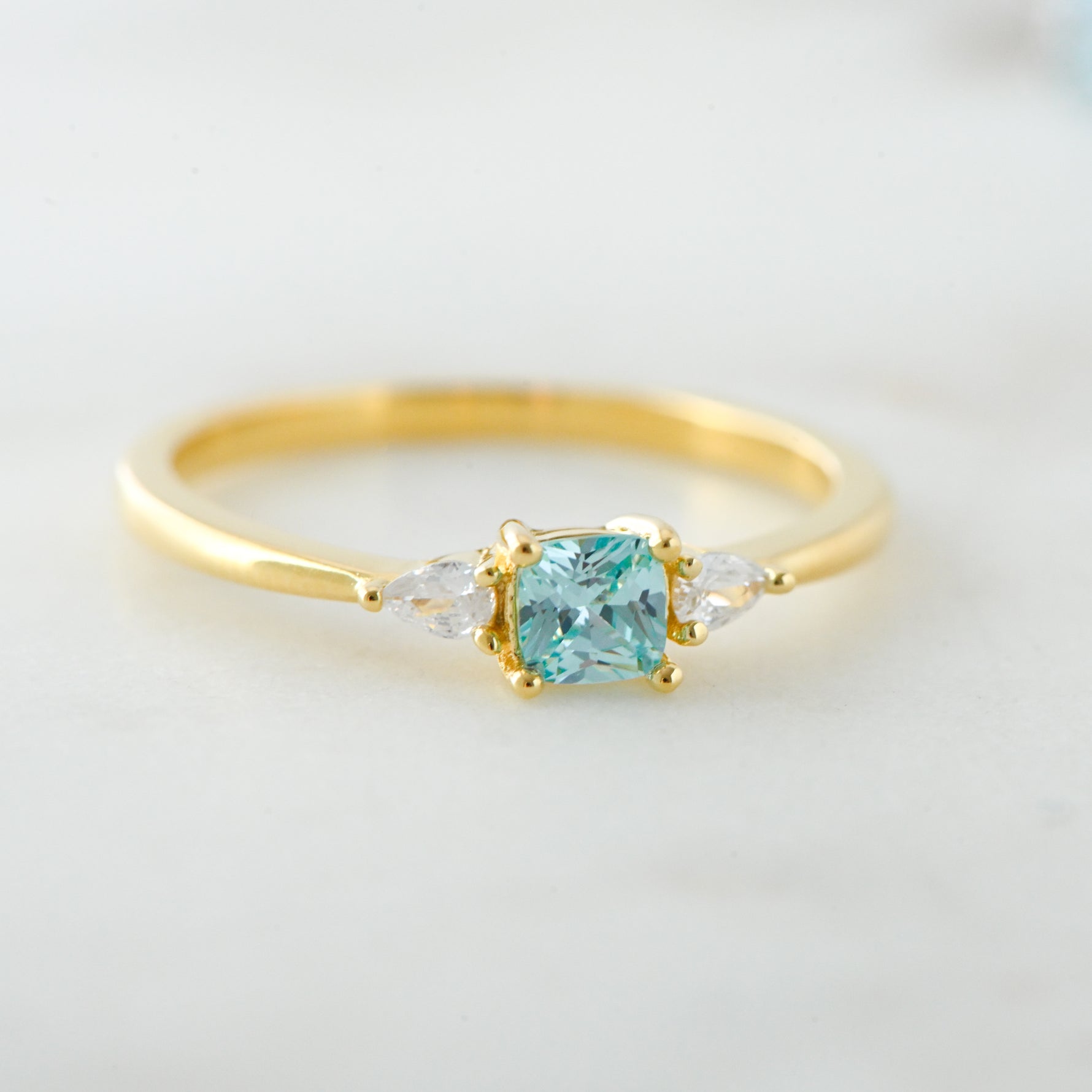 Upclose image of aquamarine cushion cz ring in gold. 