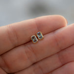 Closeup image of dainty gold aquamarine baguette stud earrings. 