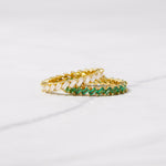 CZ diamond and emerald slanted baguette rings in gold on marble background. 