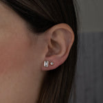 Model wearing classic gold cz diamond stud earrings including an emerald cut stud and a round bezel stud.