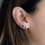 Model wearing dainty gold black onyx stud earrings. 