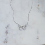 Sterling silver butterfly pendant necklace on marble background.