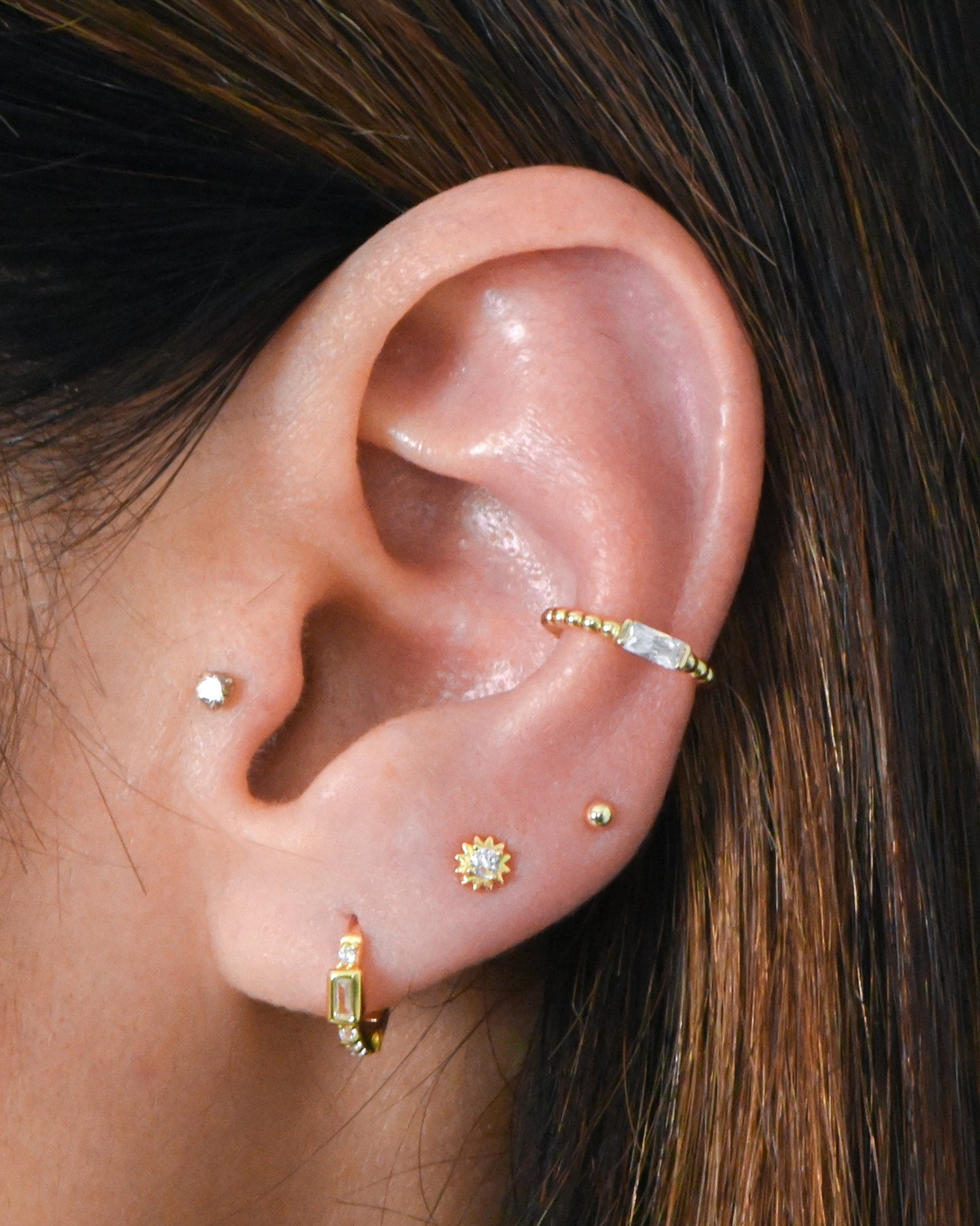 Dainty huggie and stud earrings in gold on model.