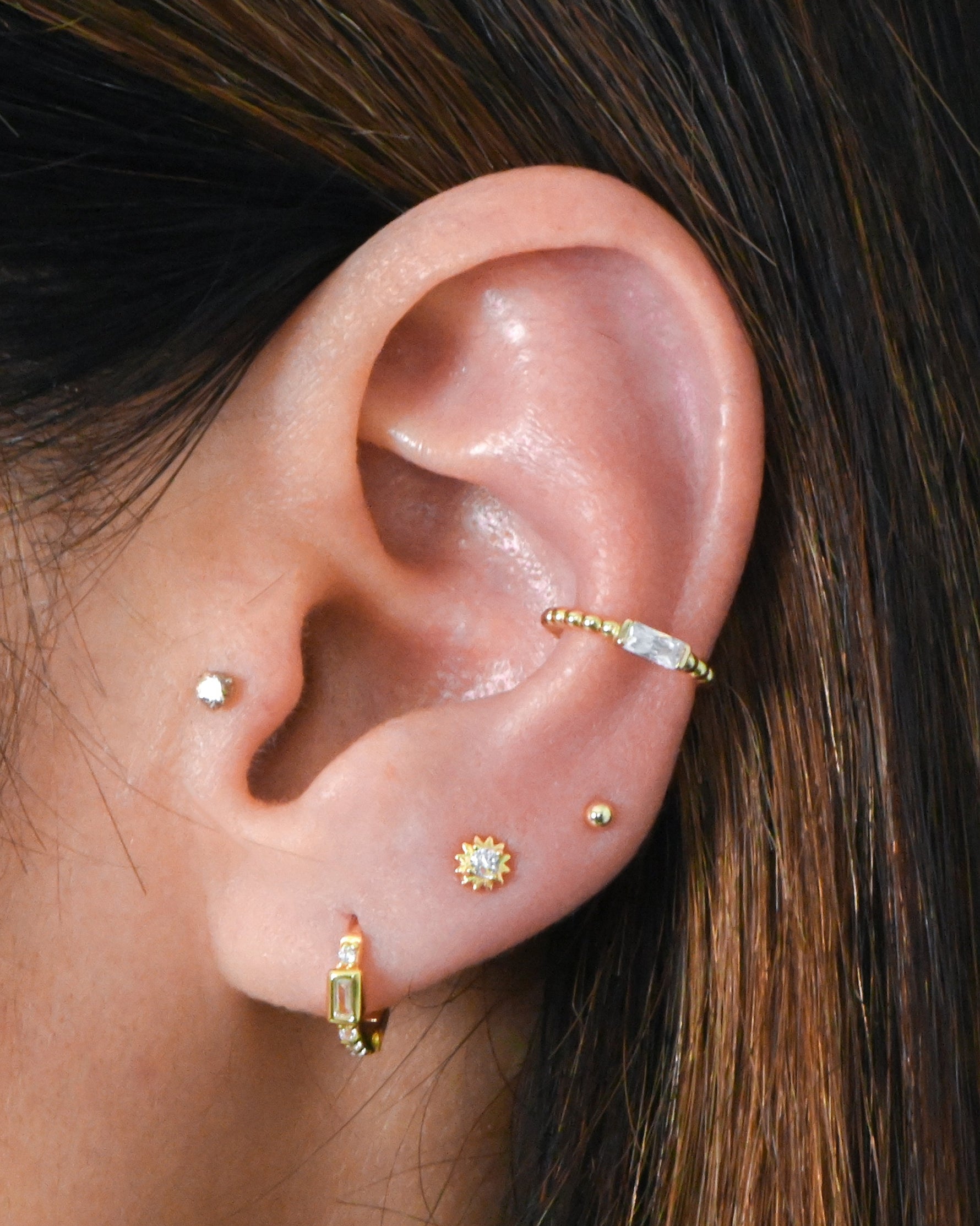 Dainty huggie and stud earrings in gold on model.