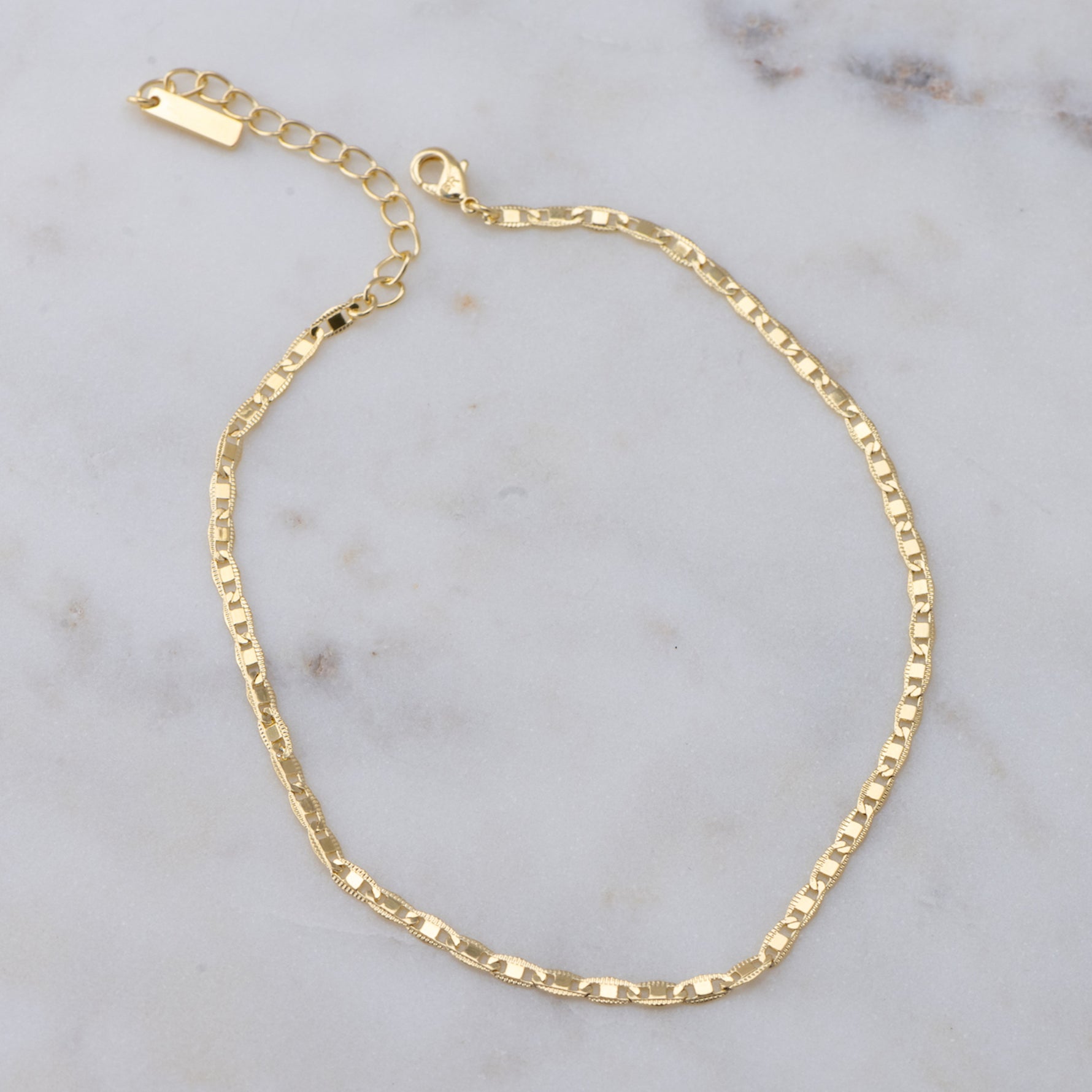 Gold shiny plain ankle bracelet on marble background