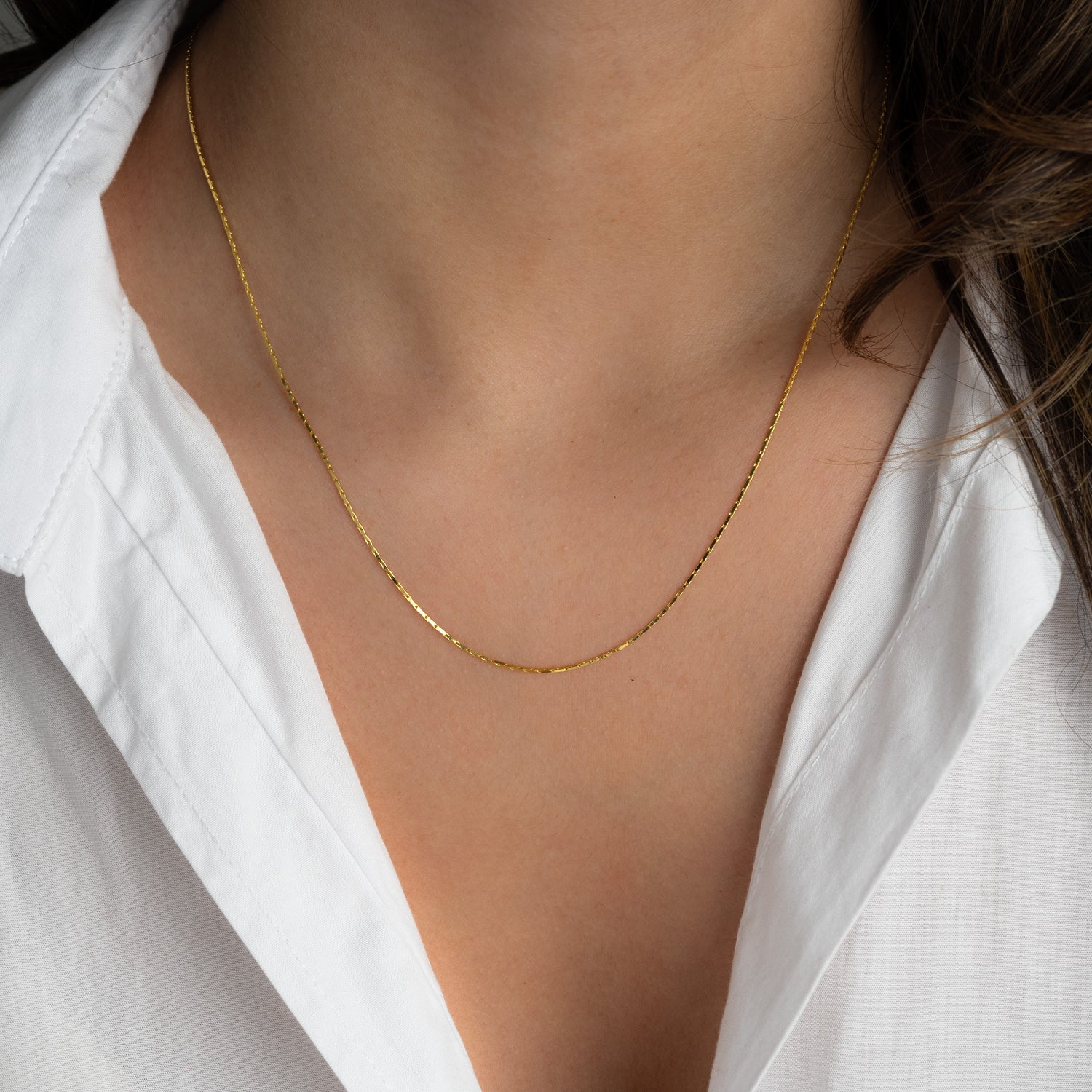 Model wearing minimalist gold thin chain necklace.