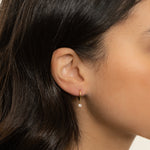 Model wearing cz diamond charm huggie earrings
