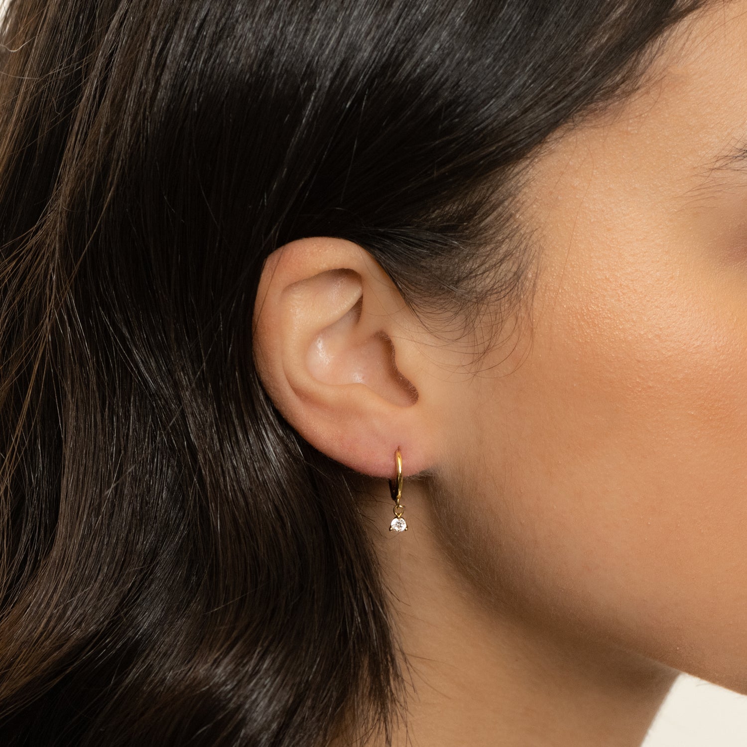 Model wearing cz diamond charm huggie earrings