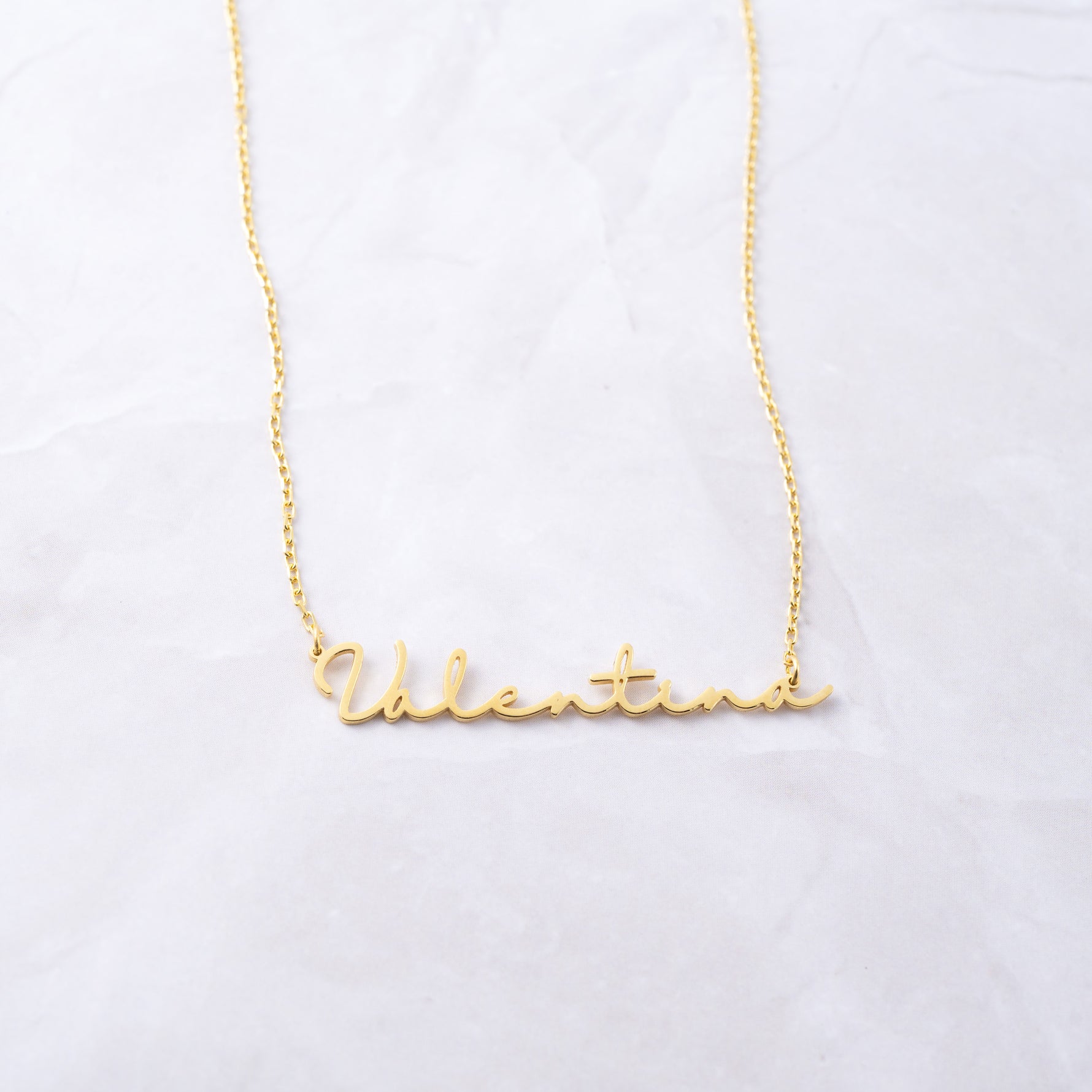 Gold custom script necklace on marble background