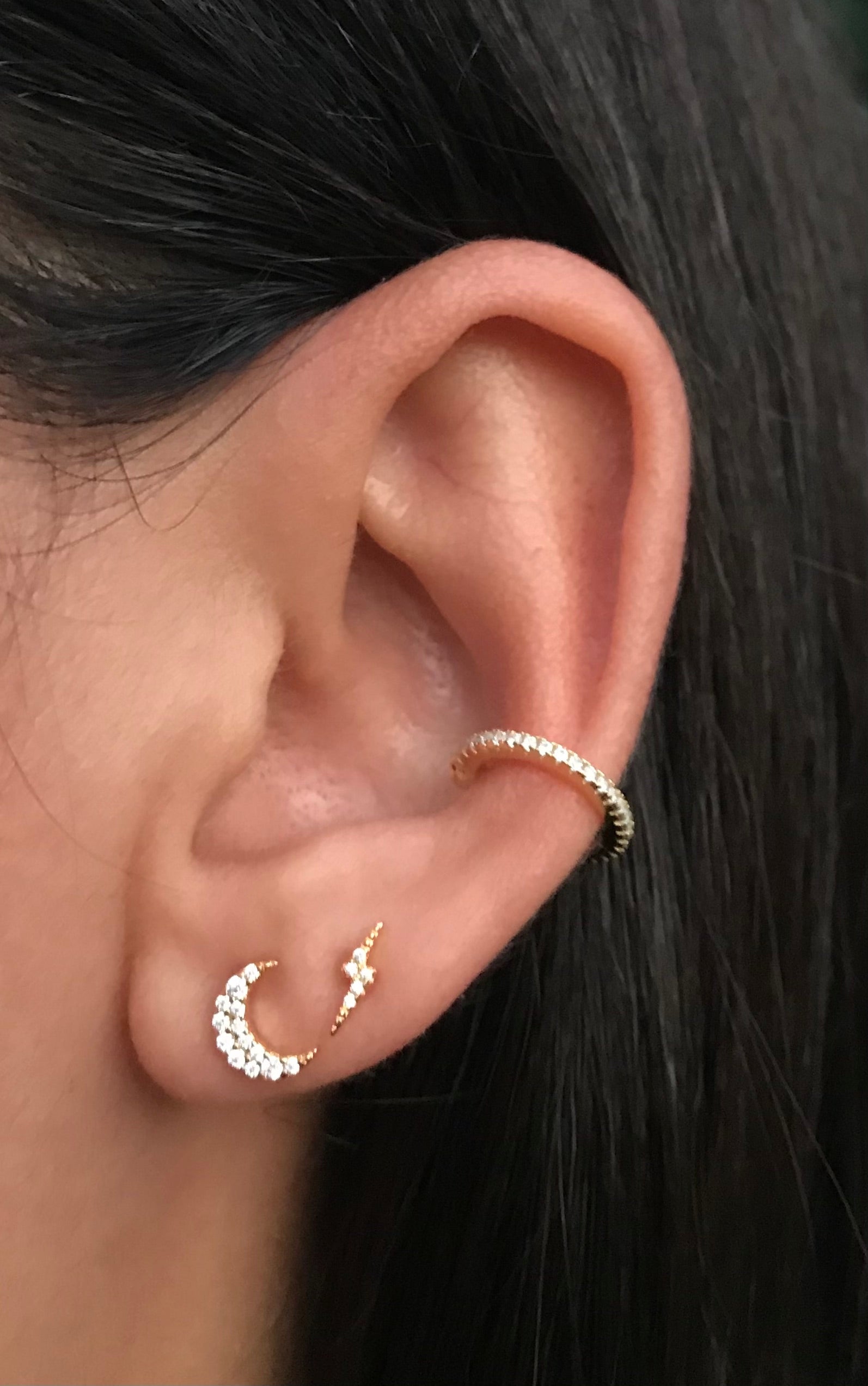 Moon celestial earring stack featuring a moon, a lightning bolt, and a cz ear cuff on a model. 