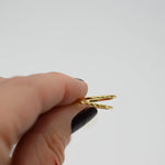 Model holding two gold dainty textured rings.