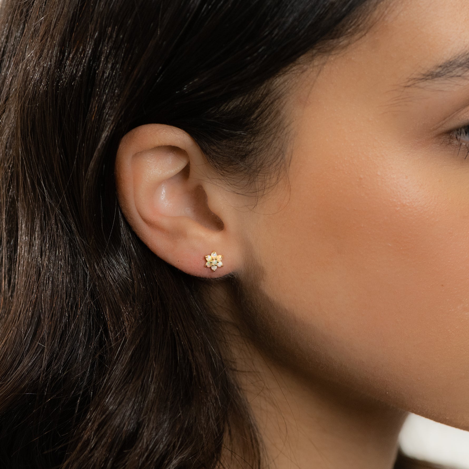 Model wearing minimalist opal flower stud earrings.