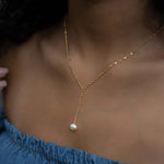 Model wearing dainty pearl lariat necklace in gold.