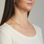 Model wearing ruby gold birthstone beaded necklace.