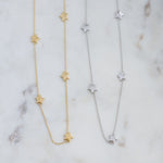 Gold and silver plain star collar necklaces on marble background.