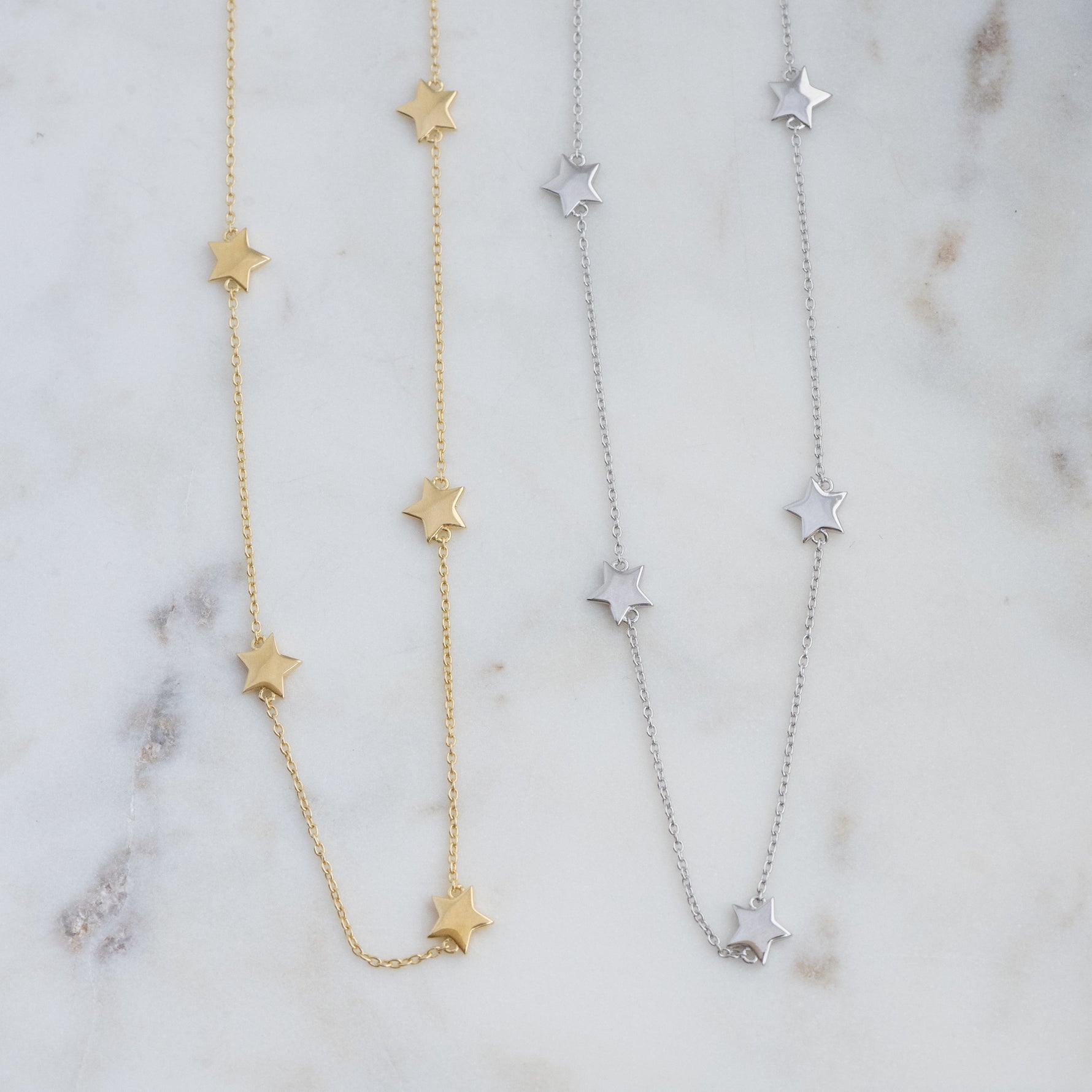 Gold and silver plain star collar necklaces on marble background.