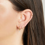 Model wearing dainty gold cz earrings paired with minimalist huggie earring.