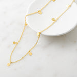 Dangling disc charm necklace on a gold chain. 