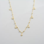 Boho chic gold delicate charm necklace on plain background. 