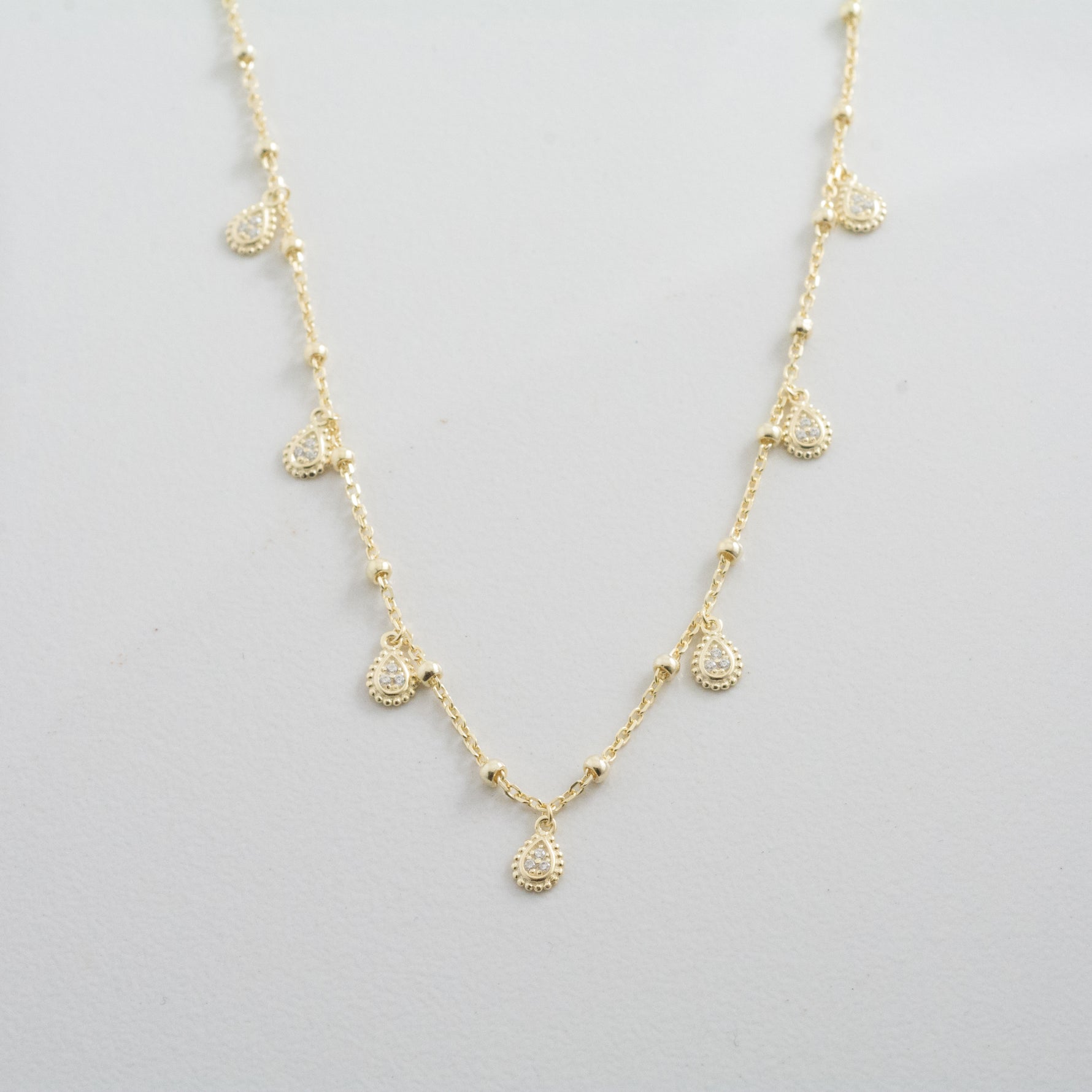 Boho chic gold delicate charm necklace on plain background. 